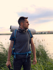 Wall Mural - A man is walking through a field with a backpack on. Scene is peaceful and serene, as the man is surrounded by nature