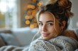A beautiful woman in a cozy sweater gives a content smile in a warmly lit home environment
