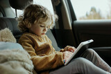 Fototapeta  - Young Girl Engaged with Tablet While Riding in Car