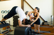 Pilates trainer assisting client on reformer bed