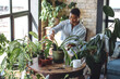 Concept of wellbeing, relaxation, work life balance, simple pleasures. Beautiful smiling plus size African American woman is doing home gardening, repotting, taking care about plants