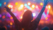 A woman enjoying a concert, lifting her arms in the air with the stage lights casting vibrant hues over her. Shallow depth of field, blurred background.