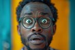 © Larisa AI - Striking close-up of an African man with wide, surprised eyes behind circular glasses on a contrasting orange background
