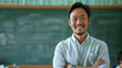 Confident middle-aged male teacher or professor standing in front of green chalk board with folded arms smiling