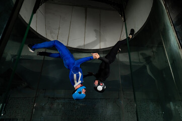 Wall Mural - A man and a woman enjoy flying together in a wind tunnel. Free fall simulator