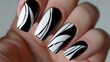 Bold graphic lines in black and white on a set of nail tips creating a modern and edgy look. .