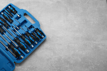 Poster - Set of screwdrivers in open toolbox on grey textured table, top view. Space for text
