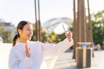 Wall Mural - Asian woman using mobile phone taking selfie or vlogging during jogging exercise at city street in the morning. Healthy girl do sport training running workout with using gadget device in the city.