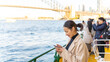 © CandyRetriever  - Asian woman using mobile phone during travel on ferry boat crossing harbor in Sydney, Australia. Attractive girl enjoy urban outdoor lifestyle travel in the city with gadget device on holiday vacation