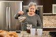 Hispanic senior woman making coffee in the kitchen. 