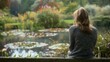A woman sits on a bench in a secluded garden back to the camera as gazes at a beautiful pond filled with lilies. The gentle . .