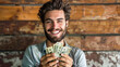 Man with a bright smile holding money - Handsome smiling man holds a fan of dollar bills against a wooden backdrop