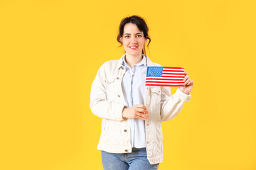 Beautiful young woman with USA flag on yellow background