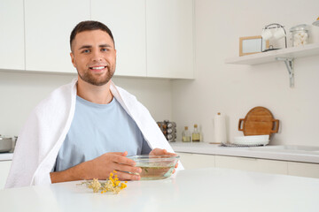 Wall Mural - Young man doing steam inhalation at table in kitchen