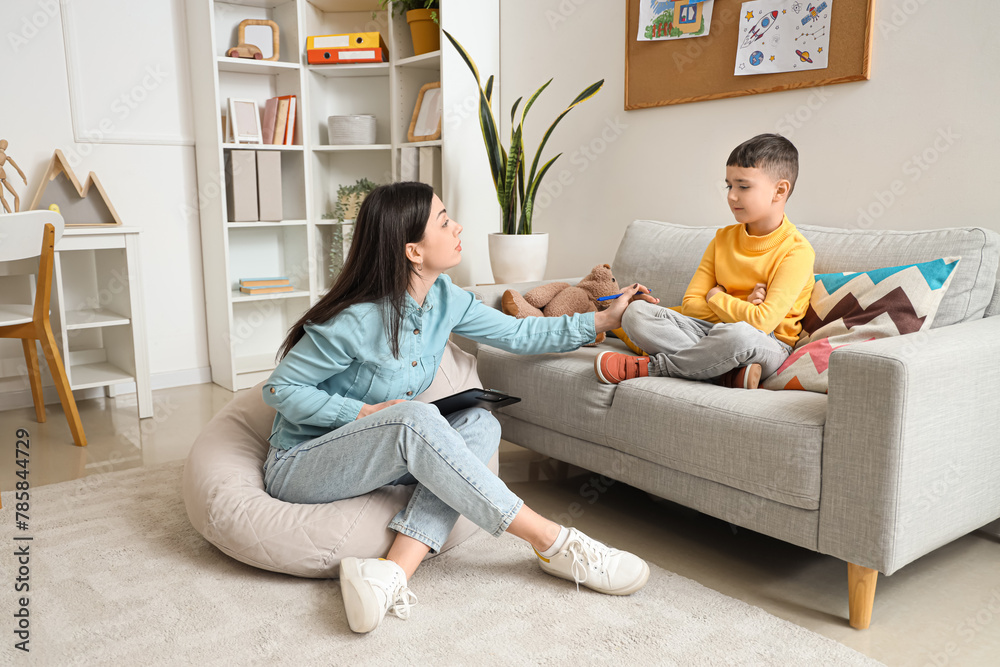 Female psychologist working with upset little boy in office