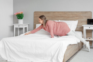 Wall Mural - Pretty young woman making bed in light bedroom