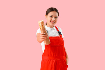 Wall Mural - Female Asian courier with doner kebab on pink background