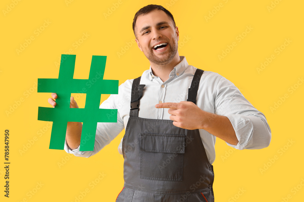 Male gardener pointing at hashtag on yellow background
