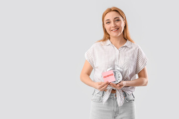 Wall Mural - Mature woman holding paper with word MENOPAUSE and alarm clock on light background