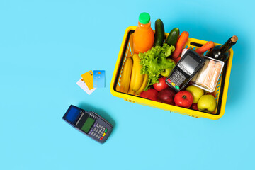 Poster - Full shopping basket with payment terminal and credit cards on blue background