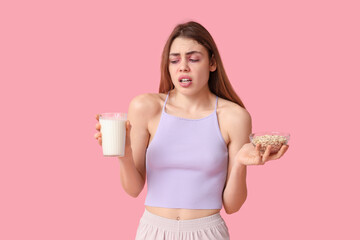 Poster - Young woman with glass of milk and bowl with nuts suffering from allergy on pink background