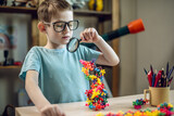 Fototapeta  - A child boy in the children's room is playing with a toy constructor for teaching the science of chemistry. Assembling molecules from elements. Children's scientific education