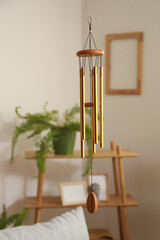 Poster - Golden wind chime hanging in light living room, closeup