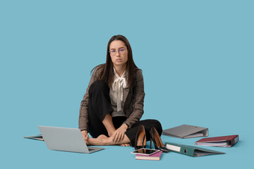 Sticker - Tired young businesswoman with laptop and office folders sitting on blue background