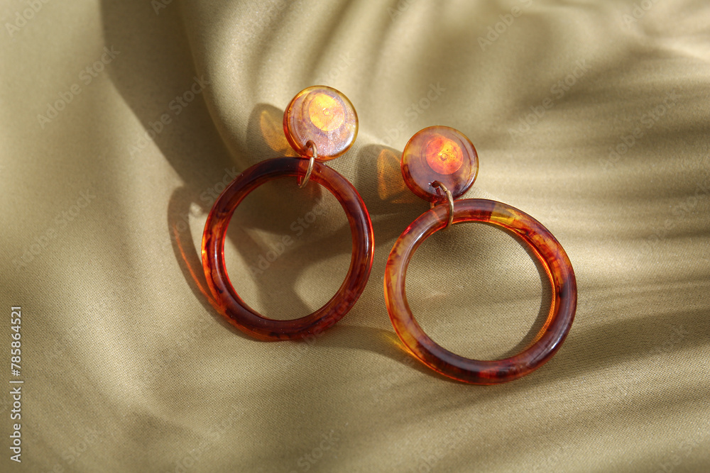 Beautiful earrings on light fabric background