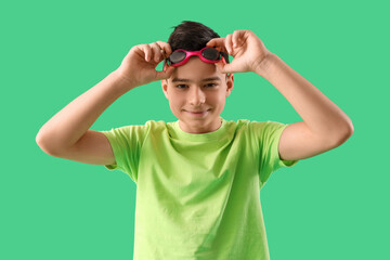 Wall Mural - Cute little happy boy with goggles on green background