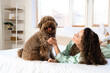 Young woman with funny poodle lying in bedroom