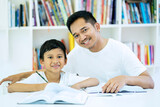 Fototapeta Zwierzęta - Picture of young father and son studying