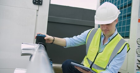 Sticker - A Engineer man looking inspecting maintenance insulated pipelines valve pump control on the roof at an industrial site, serious stressed face