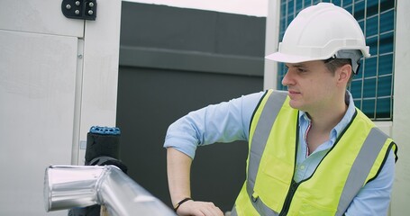 Wall Mural - A Engineer man looking inspecting maintenance insulated pipelines valve pump control on the roof at an industrial site, serious stressed face