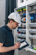 © puhimec - Man, an electrical technician working in a switchboard with fuses.
