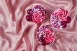 Lovely cupcakes with pink rose icing and sprinkles decoration on soft silk fabric wavy background. Traditional American sweet baked dessert. Top shot, selective focus, horizontal orientation