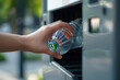 close up of hand putting plastic bottle to recycling machine