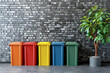 multicolored trash bins and tree in pot over brick wall background with copy space