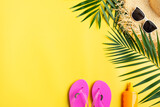 Fototapeta  - Vacation travel planning simple theme of straw hat sunglasses flip flops and palm leaves on uniform yellow background flat lay with copy-space