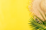 Fototapeta  - Vacation travel planning simple theme of straw hat and palm leaves on uniform yellow background flat lay with copy-space