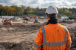 Construction Worker Overseeing Excavation Site With Machinery