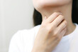 sore throat pain. Closeup of young woman sick holding her inflamed throat using hands to touch the ill neck in blue shirt on gray background.
