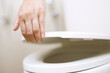 man's hand opening the toilet lid.