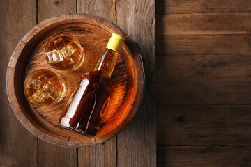 Canvas Print - Whiskey with ice cubes in glasses, bottle and barrel on wooden table, top view. Space for text