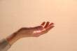 © New Africa - Woman holding something in hand on beige background, closeup
