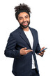A cheerful man in a business suit holding a smartphone and pointing at it, on a white isolated background, concept of technology use in business
