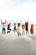 © Xavier Lorenzo - Vertical photo of happy multiracial people jumping together outdoors. Friendship concept with group of young friends from diverse cultures and races having fun with city background. Copy space.