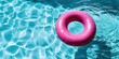 Pink pool float in the blue swimming pool. Inflatable ring seen from above in sparkling blue water with copy space. Summer leisure, vacation concept. Top view. Vivid pool ring floating. Water ring