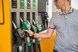 Man holding a gasoline nozzle in his hand on self-service filling station, but focus on cheaper diesel in Europe