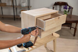 Fototapeta  - Handyman fixing over tight drawer slides rail of bedside table.